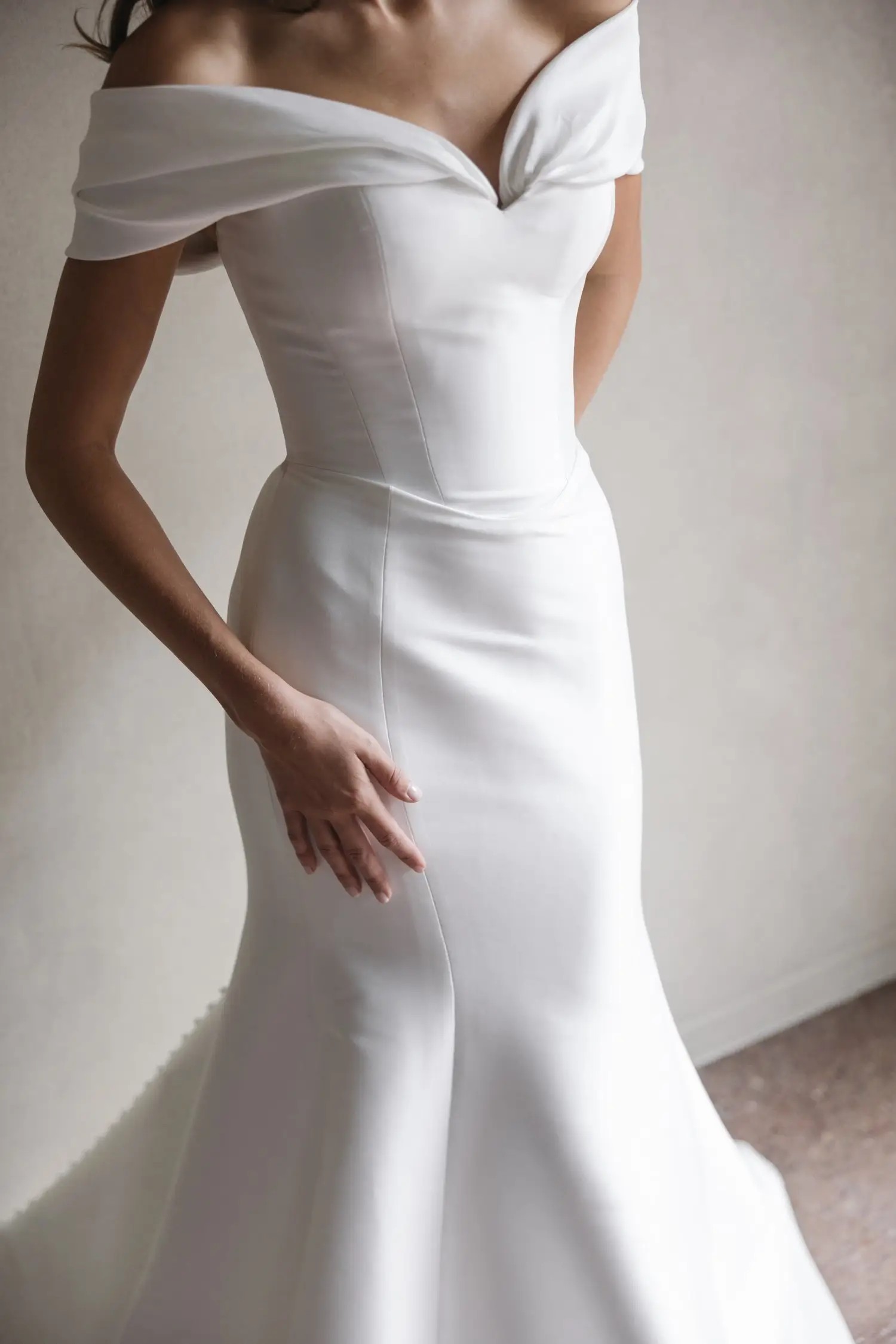 model is wearing an off the shoulder fit and flare bridal dress by trish peng