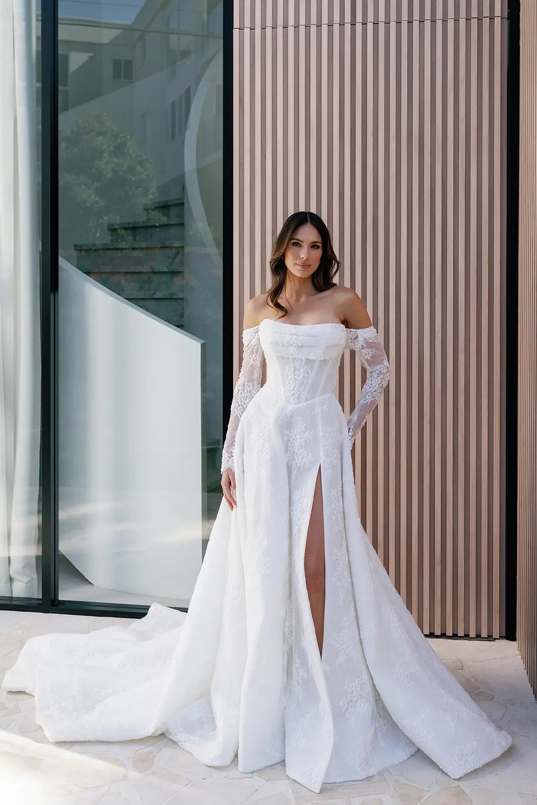 Model is wearing an a-line lace wedding gown with a basque waist 