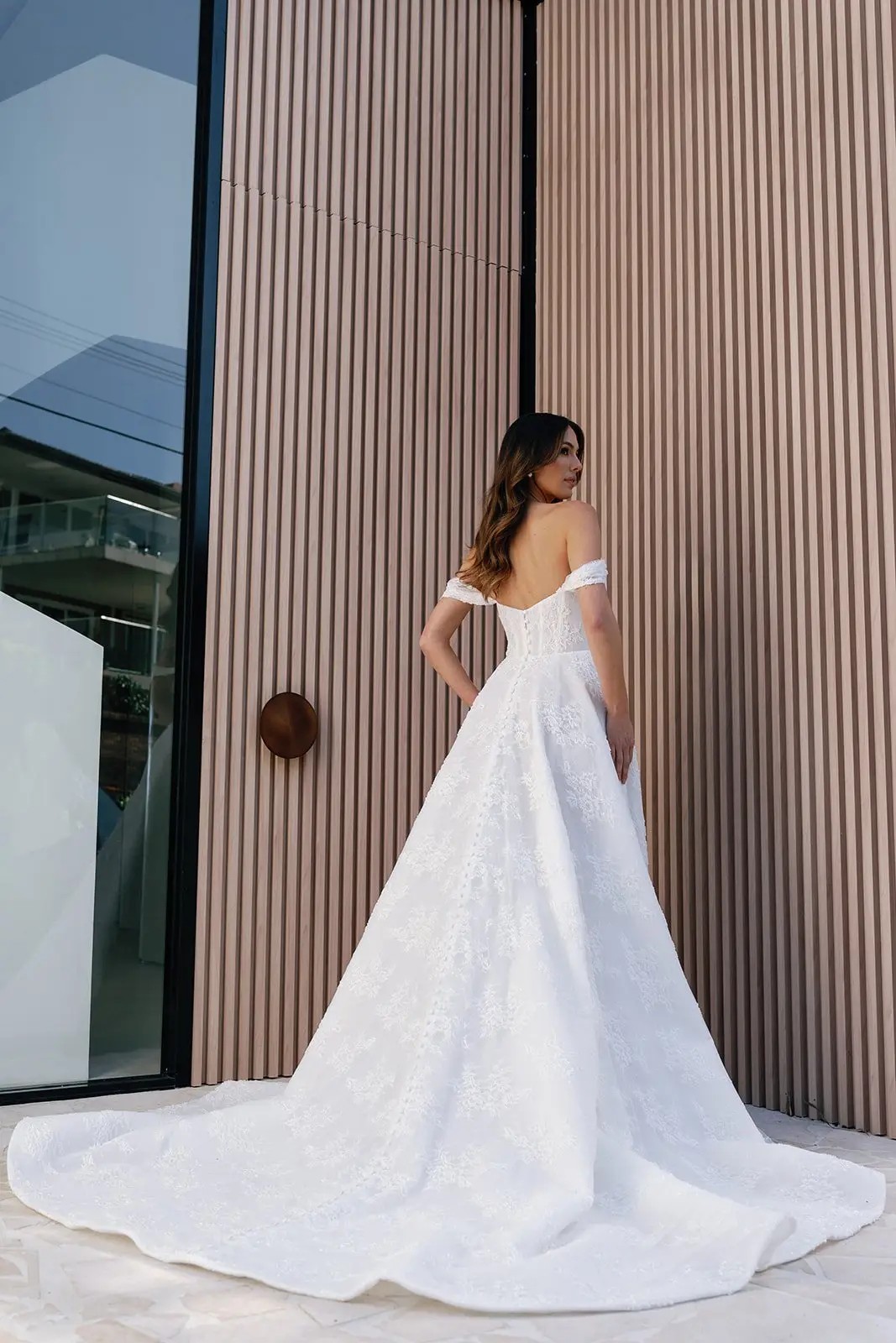 Model is wearing an a-line lace wedding gown with a basque waist 