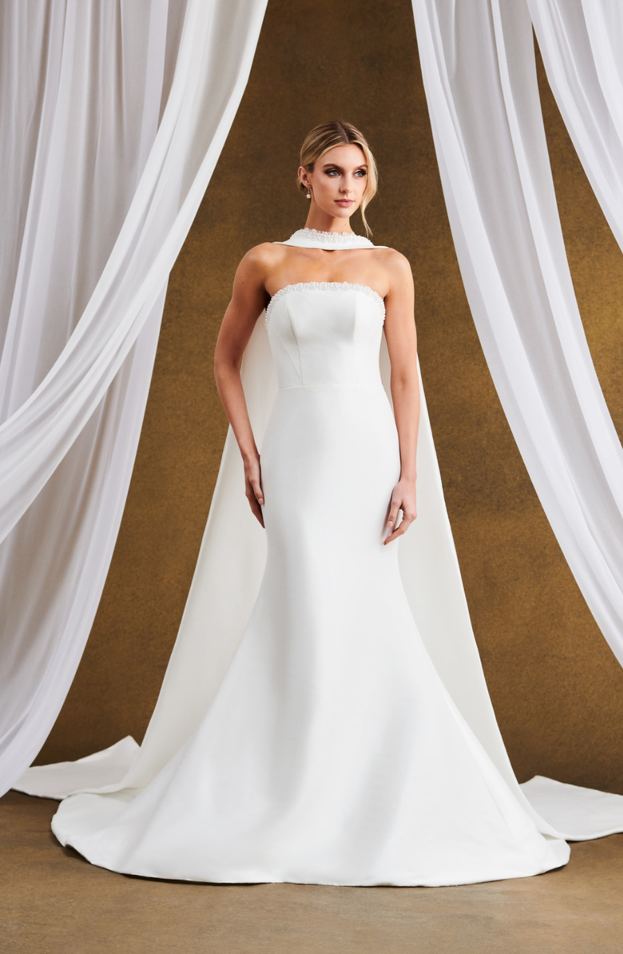 Model is wearing a Kelly Faetanini #Selina gown, a Mikado fit-to-flare style with a pearl- and bead-trimmed neckline, structured bodice, and detailed seams.