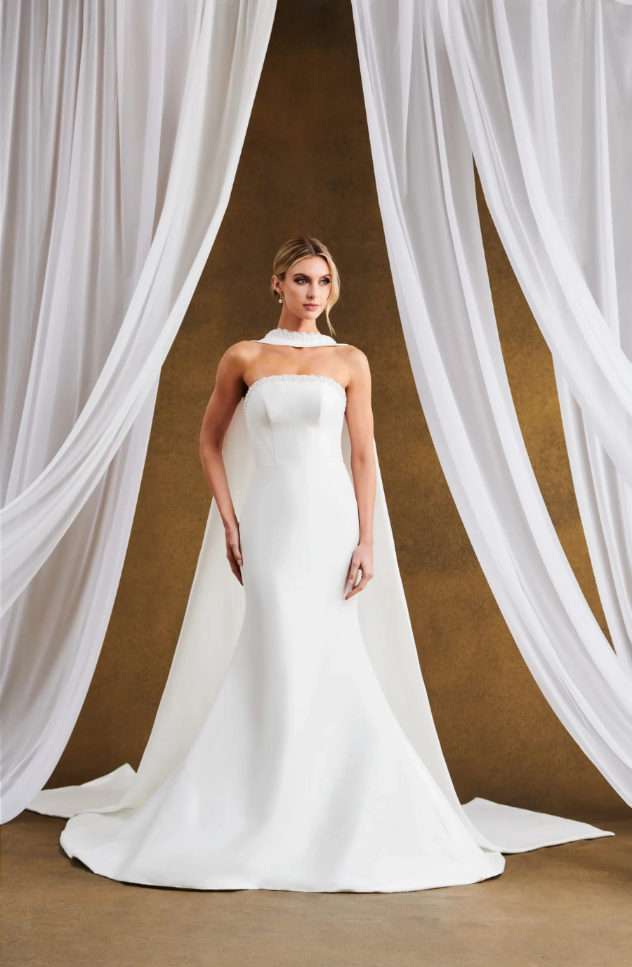 model is wearing a strapless fit and flare wedding dress with a scarf