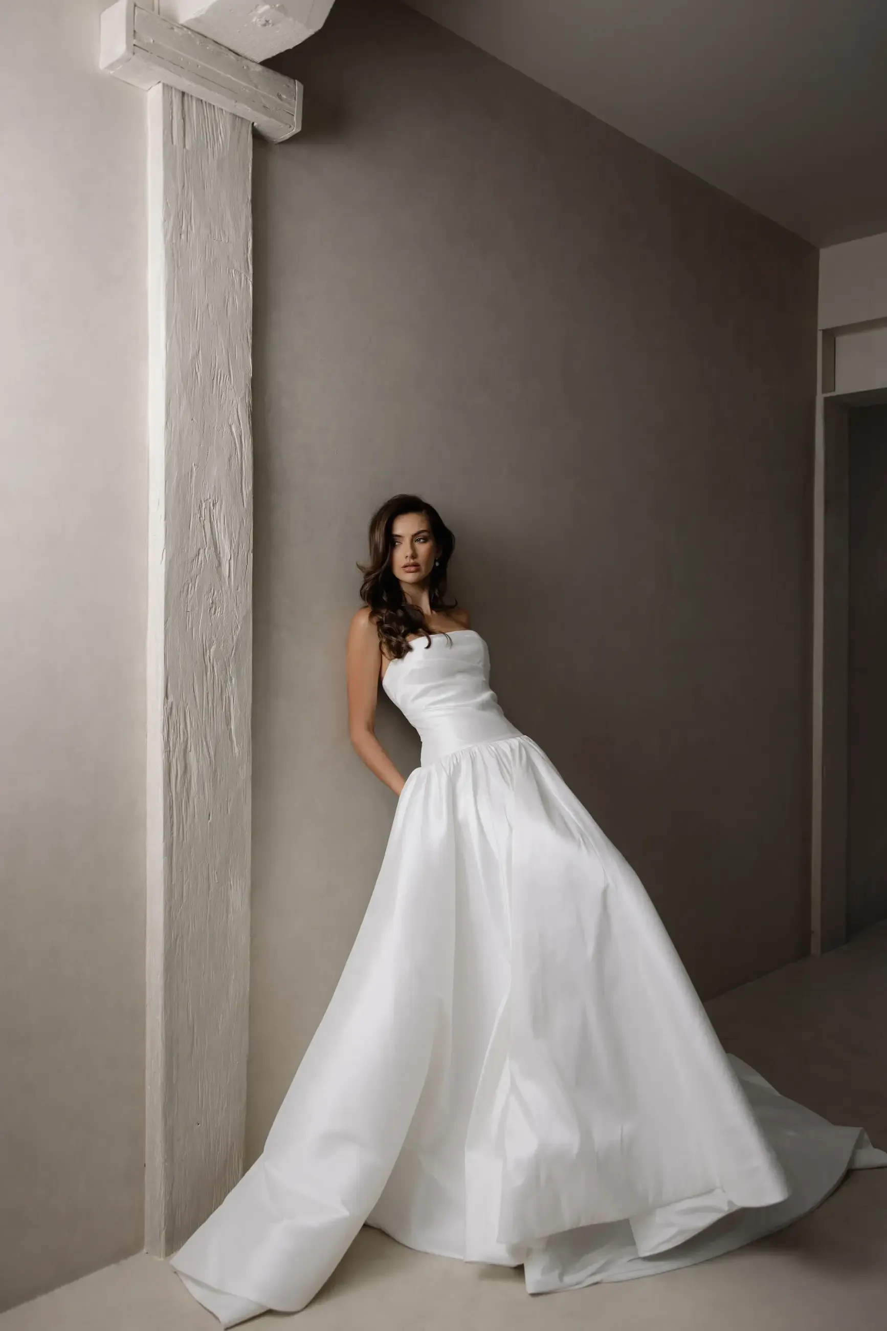 Model is wearing a Trish Peng #Aneta gown, with a modern drop waist, luxurious stretch Mikado fabric, expert ruching through the bodice, and a flowing A-line skirt.