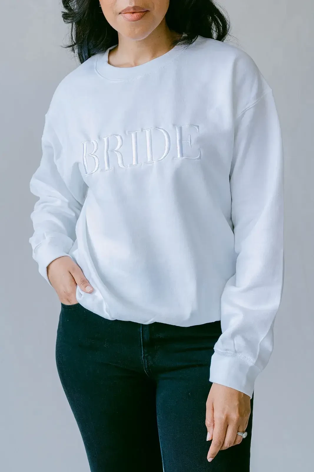 model is wearing a white sweatshirt that says bride on it