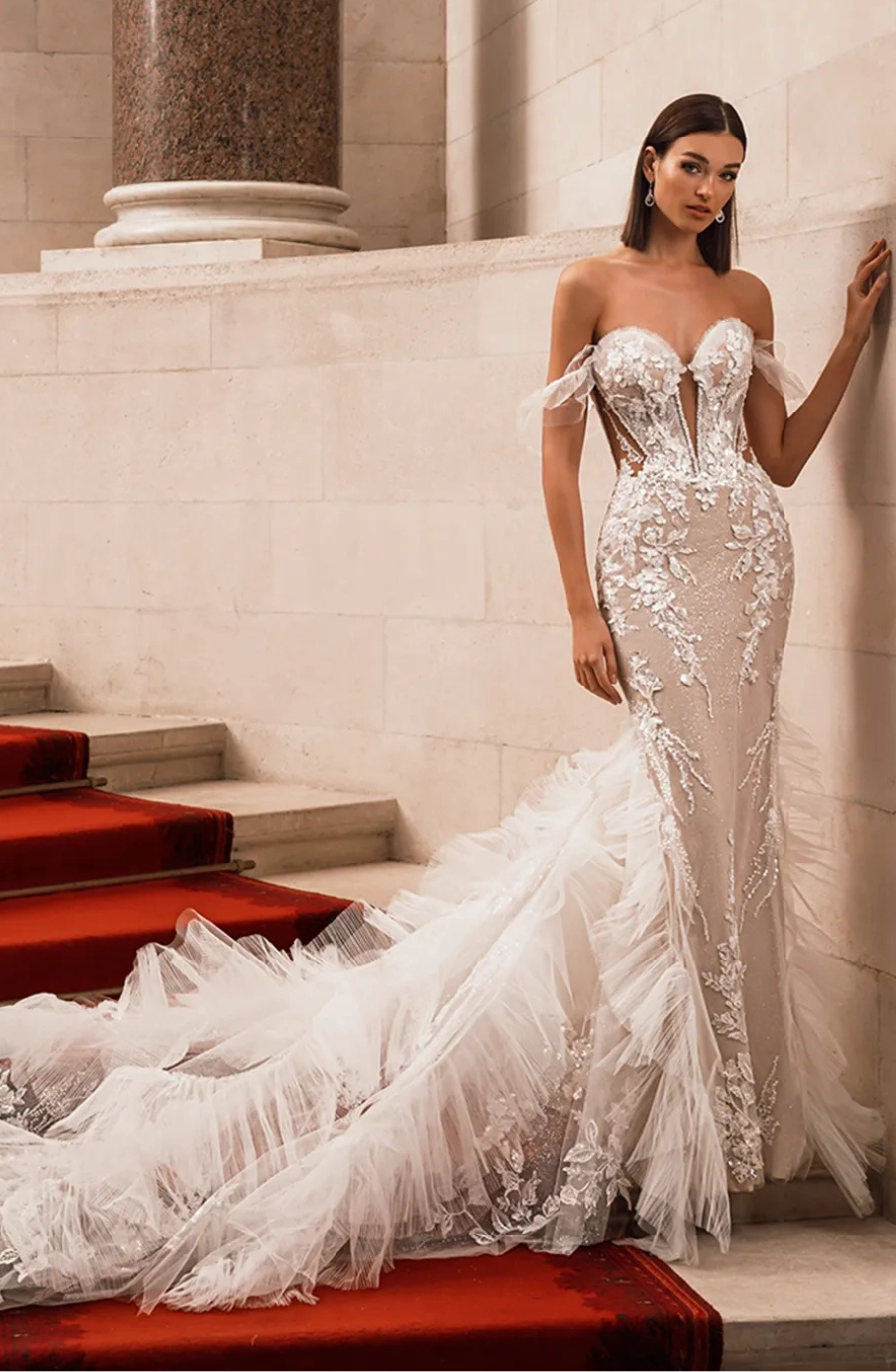 model is wearing a glamorous off the shoulder fit and flare bridal gown with feathers on the train