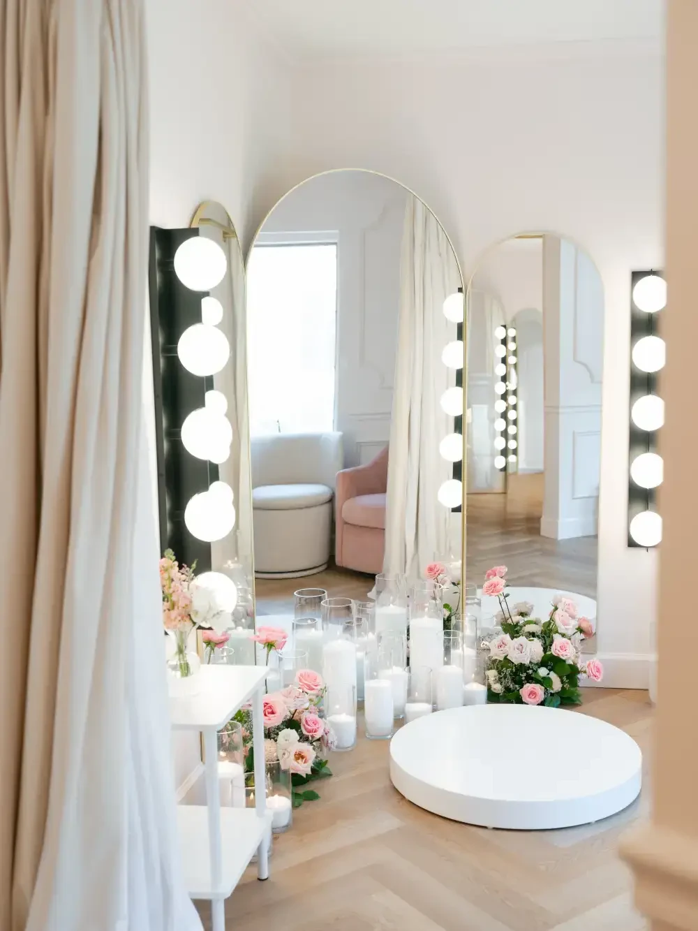Interior space featuring mirrors, soft lighting, and floral arrangements with candles on a wooden floor.