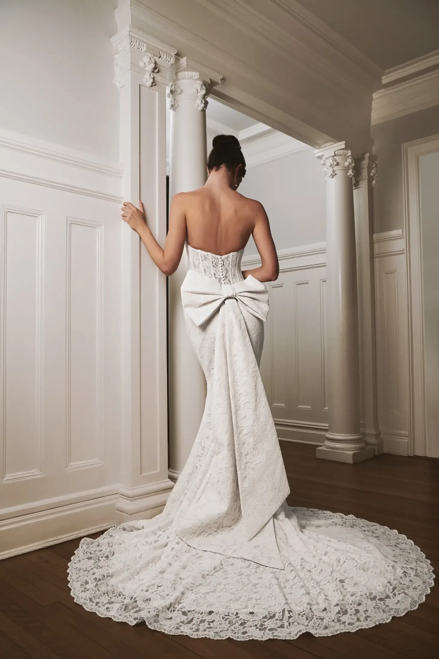 Model is wearing a Liv by Kelly Faetanini #Ruth gown, featuring a scalloped hem, detachable bow and streamers, and an illusion corset back.