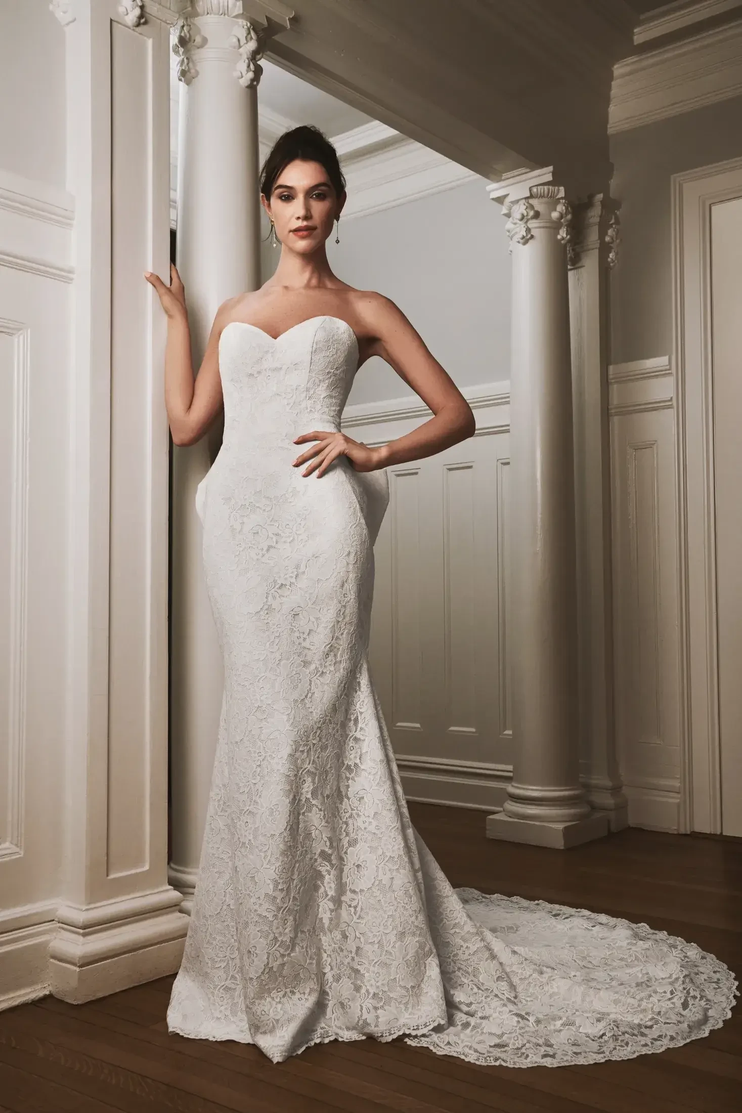 Model is wearing a Liv by Kelly Faetanini #Ruth gown, featuring a scalloped hem, detachable bow and streamers, and an illusion corset back.